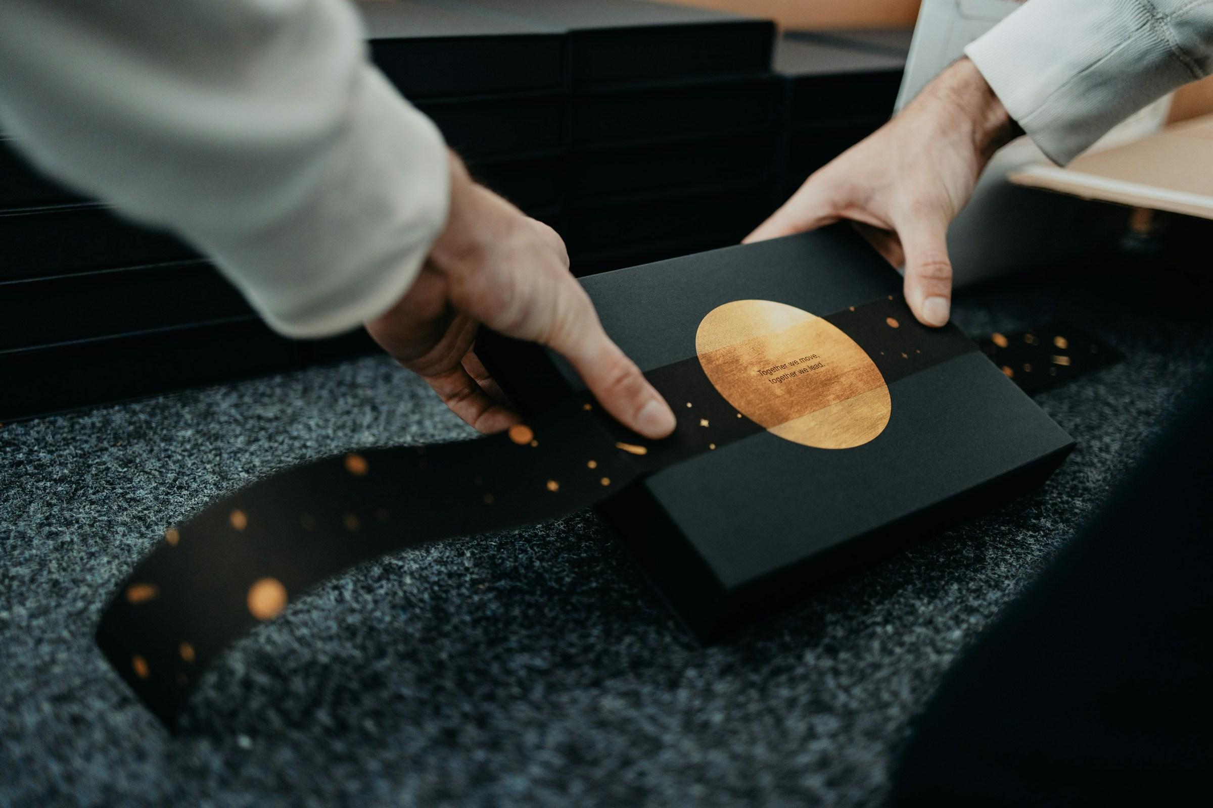 Hands finishing luxury packaging with foil seals on the production path