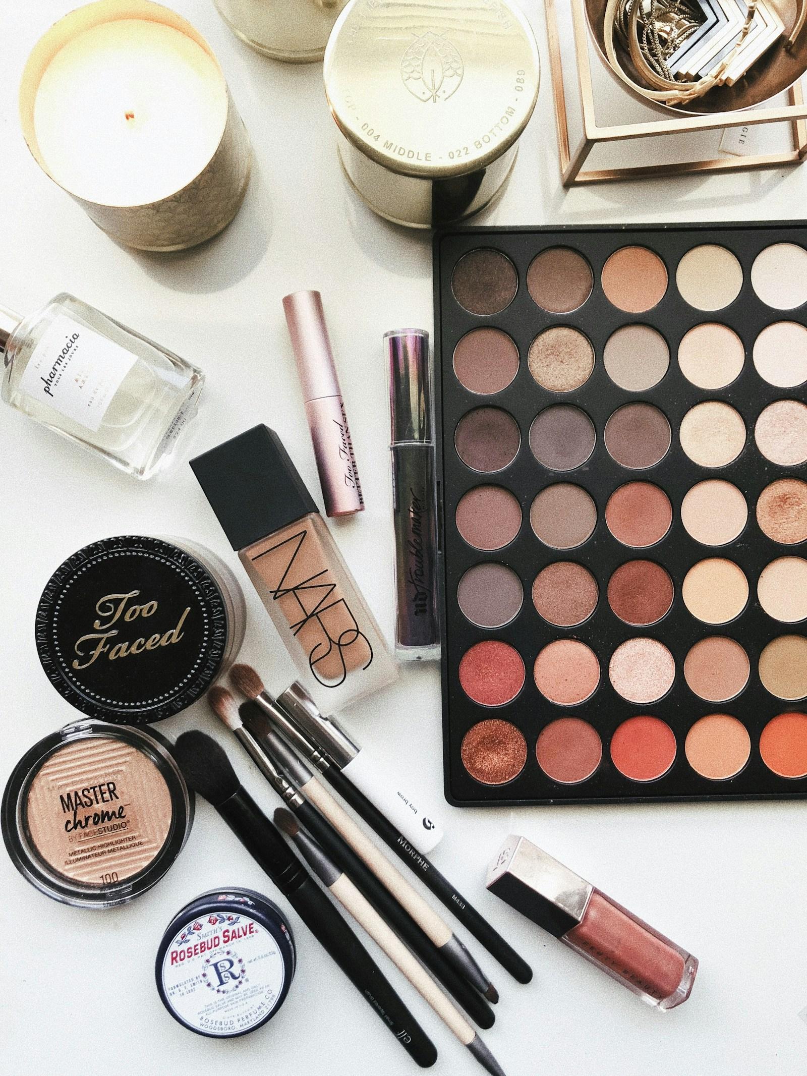 Color cosmetics flatlay with eyeshadow palette, compact, lipstick, and mascara